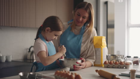 loving-mother-is-teaching-her-little-daughter-to-cook-cake-mom-and-child-are-spending-time-together-in-kitchen